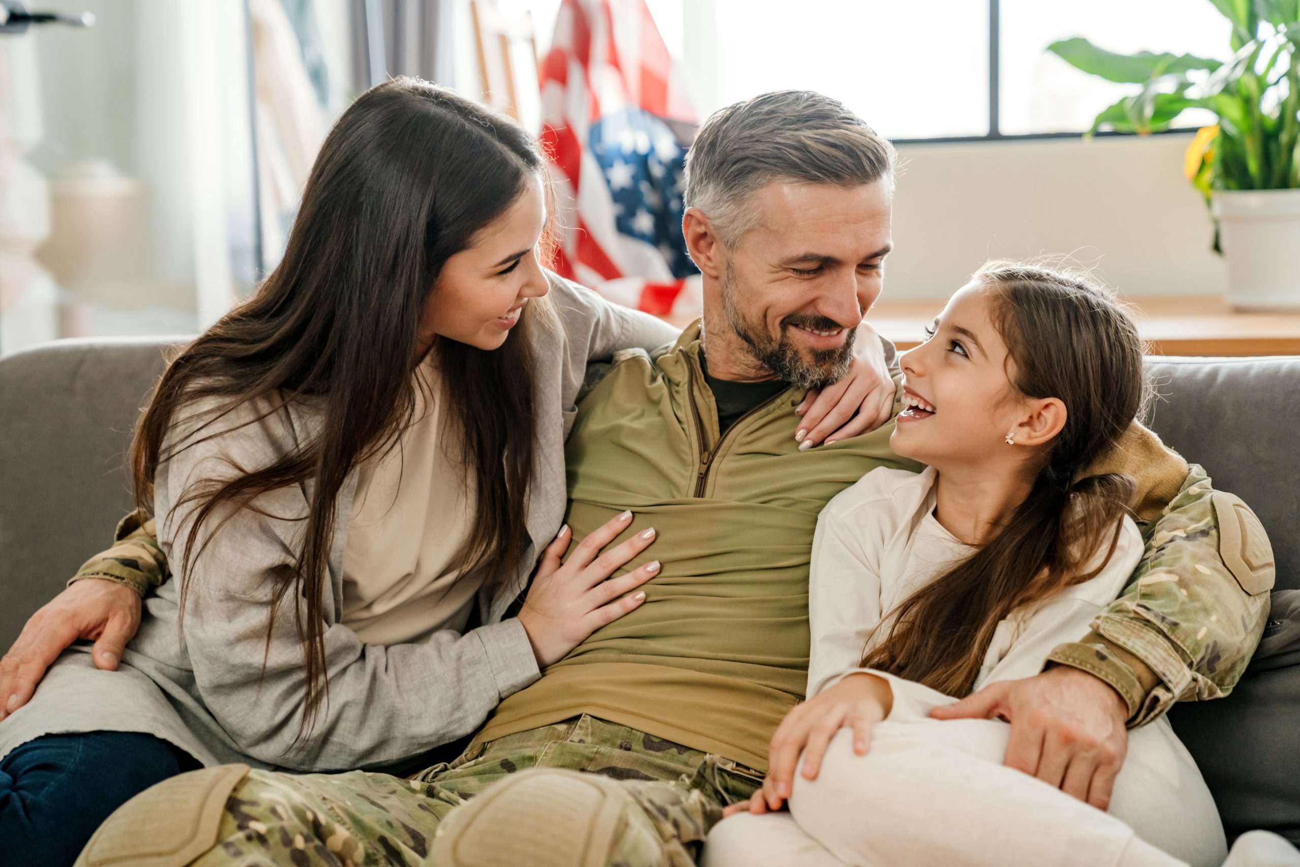happy military man hugging his family and laughing while sitting on the couch