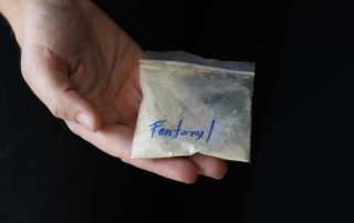Woman holding a pack with fentanyl powder to illustrate the drug addiction